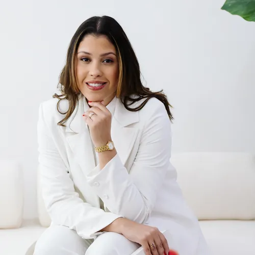 Emanuelle Mendes de branco, sentada, com o livro de DBT no colo