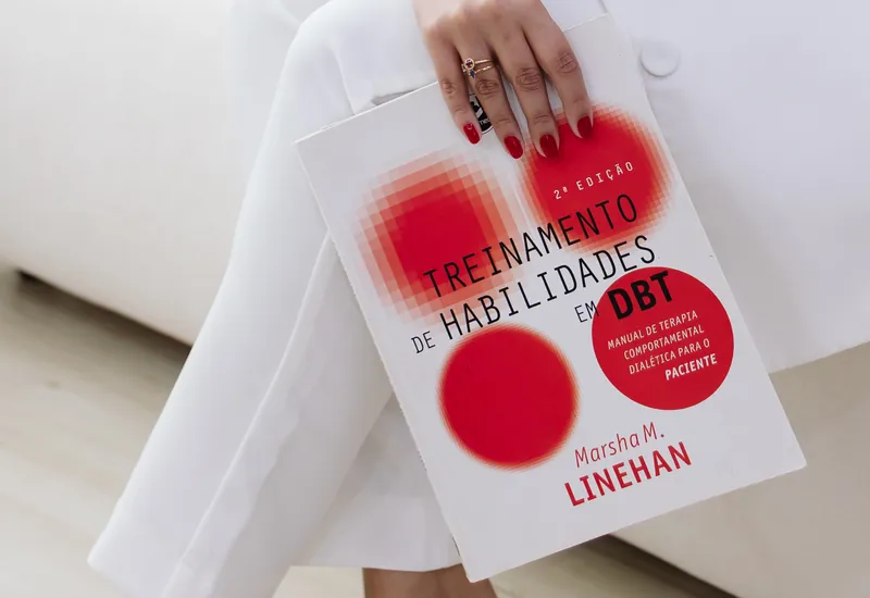Emanuelle Mendes segurando o livro de treinamento de habilidades em DBT